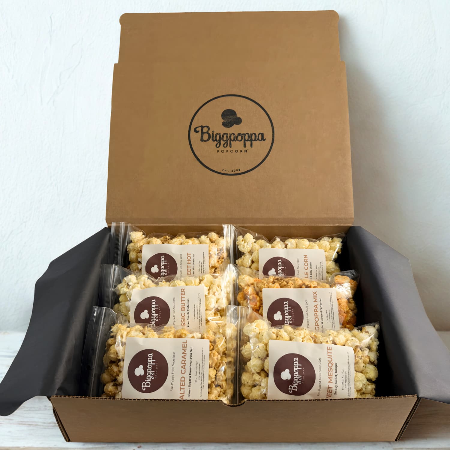 Open box of Biggpoppa Popcorn with multiple flavor packages inside.